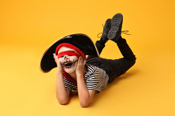 Wall Mural - Funny boy dressed like pirate on yellow background. Halloween costume