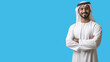 © Ahmed - Emirati Man Smiling with Crossed Arms on Isolated blue Background: Perfect for Portraits, Cultural Representation, and Marketing Materials - Capturing Confidence, Positivity, and Tradition.