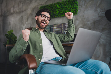 Poster - Photo of professional it specialist young man raise fists laptop computer desktop loft interior office indoors