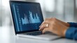 © Tana Studio - Business Professional Analyzing Financial Data on Laptop with Graphs and Charts in Modern Office Setting