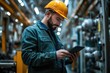 © Tendo - Technician wearing hard hat using digital tablet on shop floor in a factory.
