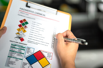 Wall Mural - action of a safety officer is marking on the chemical hazard material checklist to verify the type o