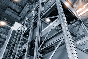 Aufkleber - A warehouse with a lot of metal shelves and a lot of light. The light is shining on the shelves and the metal structure