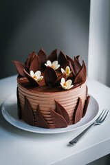 Poster - Chocolate cake decorated with chocolate flowers and leaves on a white plate