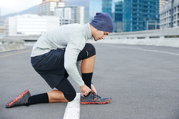 Canvas Print - Runner, man or tie sneakers in city for morning jog, fitness or getting ready for cardio workout in street. Athlete, person or prepare running shoes on urban bridge for exercise, training or marathon