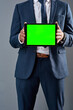 © SensSai/peopleimages.com - Hands, tablet or business man with green screen for mockup space on gray studio background. Chroma key, technology or person show advertising information, sales discount or corporate commercial offer