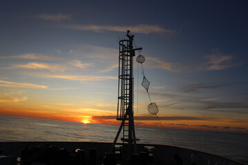 Front of fishing vessel sailing in the North Sea with a sunset in front of it. 