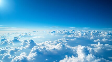 Clear blue sky with puffy clouds. The view is from above the clouds. The blue sky fades to white at the horizon. The air is calm and clear. The landscape is beautiful and peaceful.