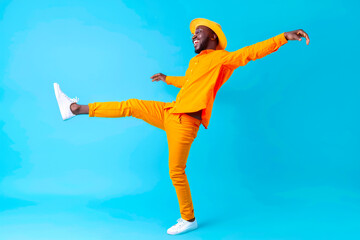 full body side view smiling fun cheerful young happy african american man in orange shirt hat stand 