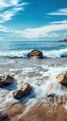 Canvas Print - Calm Sea Waves Crashing on Sandy Beach With Rocks and Blue Sky