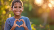 © Zhongyuan Chen - A 10-year-old boy forms a heart shape with his hands in front of his chest, smiling warmly. The soft lighting in the background highlights his kind and friendly nature.