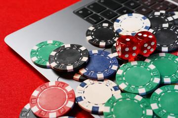 Canvas Print - Poker chips, laptop and dices on red table, closeup. Online game