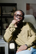 © pressmaster - Portrait of man wearing glasses and sitting in an office chair in a well-lit room, resting hand under chin, showcasing a thoughtful expression