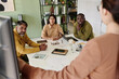 © pressmaster - Group of diverse professionals engaging in strategic discussion around conference table while leader standing and presenting ideas on electronic screen