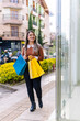 © Daniel Ching - Happy shopping woman with her products during black friday with yellow and blue bags. Incredible discounts.