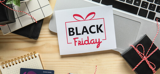 Poster - Black Friday sale greeting card with laptop, gift boxes and credit card on wooden table