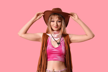 Young woman dressed as cowgirl doll on pink background