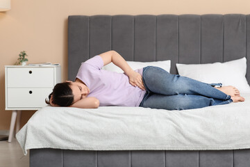 Canvas Print - Young woman suffering from cystitis on bed at home