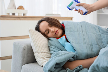 Poster - Doctor measuring temperature of sick young woman with infrared thermometer at home