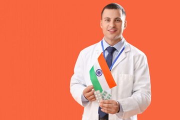 Wall Mural - Male physician with flag of India on orange background. National Doctor's Day celebration