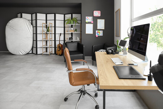 Photographer workplace with photo camera, computer and color wheel charts in modern studio