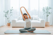 © Monster Ztudio - Happy young Asian woman practicing yoga and shoulder stretching at home sitting on floor in living room