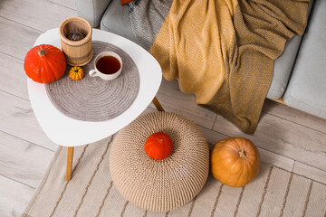 Canvas Print - Coffee table with cup of tea, pouf and pumpkins in interior of living room