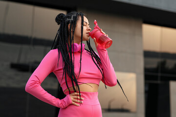 Wall Mural - Sporty young African-American trainer drinking water outdoors