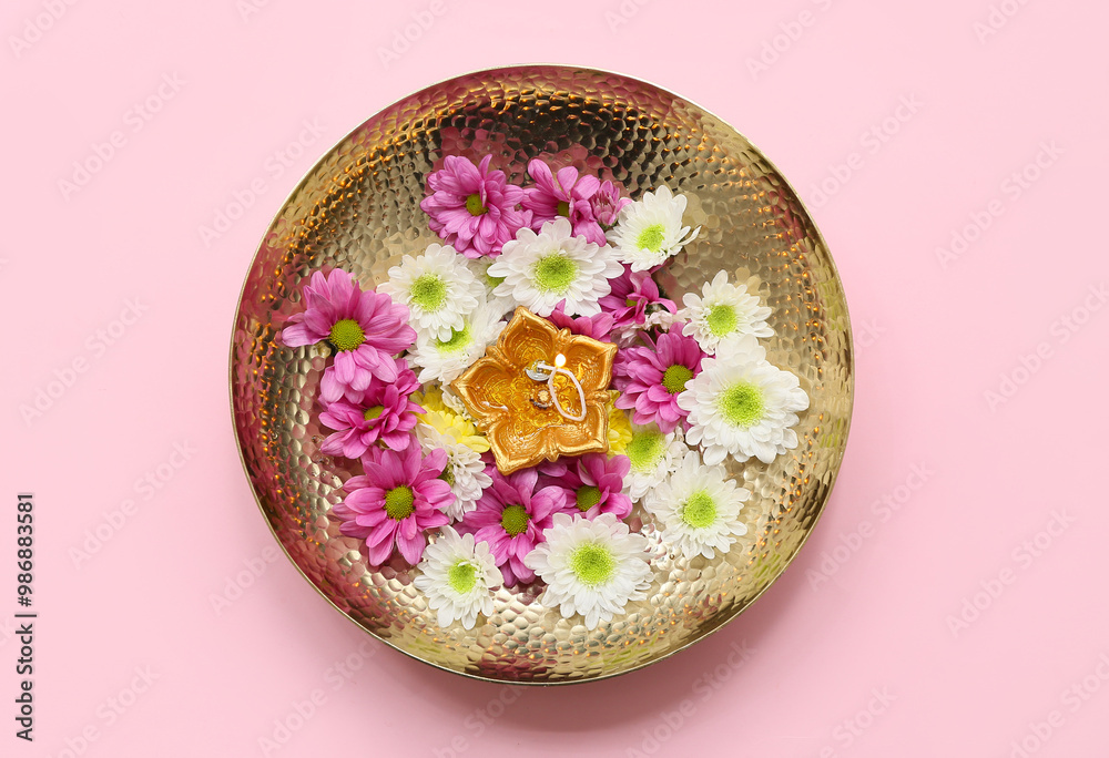 Plate with diya lamp and flowers on pink background. Divaly celebration