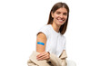 © Damir Khabirov - Portrait of happy vaccinated female smiling after getting vaccine shot. Woman holding down her sleeve to show her arm with blue bandage after vaccination