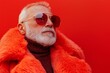 © Nataliia_Trushchenko - Man wearing a red fur coat and sunglasses. He has a beard and is wearing a red hat. Concept of old men's health, self care, fashion and beauty, healthy lifestyle