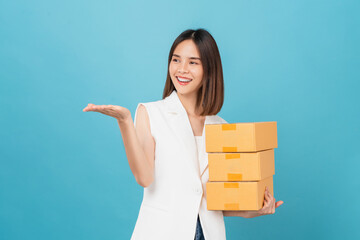 Wall Mural - Smiling beautiful Asian woman holding cardboard boxes on blue background. Concept delivery online.