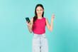 © sitthiphong - Beautiful Asian woman holding smartphone and smiling on blue background.