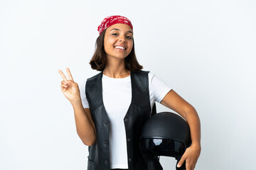 Wall Mural - Young woman holding a motorcycle helmet isolated on white smiling and showing victory sign