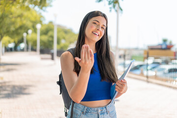 Wall Mural - Young Brazilian student woman at outdoors inviting to come with hand. Happy that you came