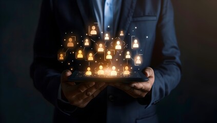 Poster - Businessman holding a tablet with digital glowing human icons, such as people or business team icons, on the screen against a dark backgroun
