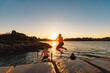 © Austockphoto - Teenage boy jumping from ledge into water in bright setting sun