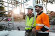 © Austockphoto - Construction workers looking and talking at the construction site.