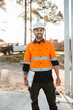© Austockphoto - A bearded man wearing a hardhat and holding a pen and clipboard.