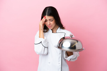 Young Italian chef woman holding tray with lid isolated on pink background with headache