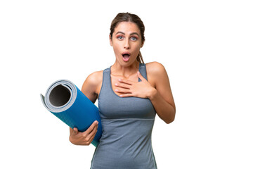 Canvas Print - Pretty Young Uruguayan sport woman going to yoga classes while holding a mat over isolated background surprised and shocked while looking right