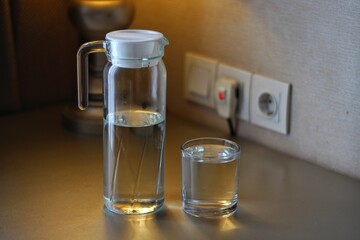 Bottle of water with glass on desk in room, closeup