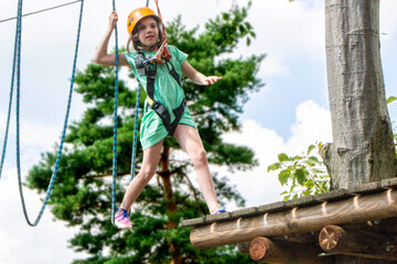 Adventure climbing high wire park - child on course in mountain helmet and safety equipment. High quality photo