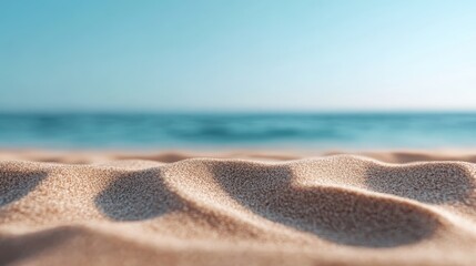 Smooth ripples in the beach sand stretch towards the horizon, where the calm blue ocean meets a sunny, clear sky, offering a tranquil and serene seaside atmosphere.