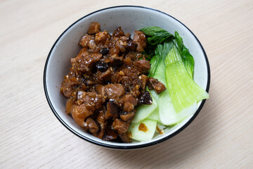 A bowl of rice topped with pork sauce and bok choy.