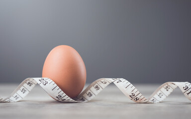 Fresh egg and measuring tape on a table symbolize the idea of eating eggs for weight loss or health. The image highlights eggs as a nutritious choice for a balanced diet and fitness goals