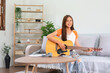© snowing12 - Concept of relaxation with music, Young woman sit on couch to playing music with acoustic guitar