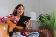 © snowing12 - Hobby concept, Young asian woman wear earphone and sit on the couch to learning music on tablet