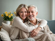 © Benedetto Riba - Una coppia matura felice che si abbraccia su un divano, con fiori sullo sfondo, in un'atmosfera di serenità e benessere