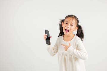 Wall Mural - Portrait Asian happy young kid girl smile making finger pointing on screen smartphone in hand, Kindergarten children attractive shopping online application isolated studio shot white background